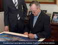 George HW Bush autographs the prints